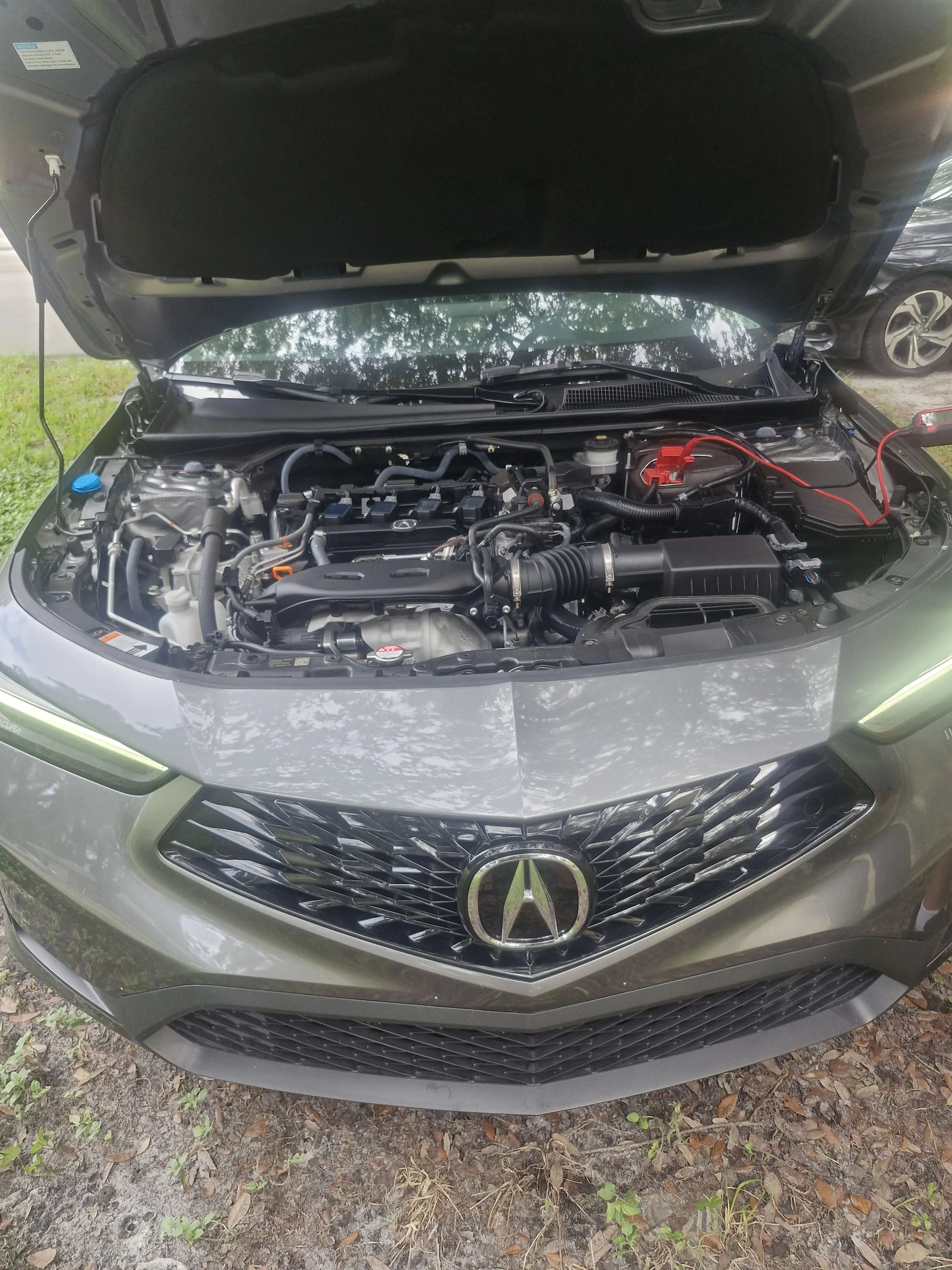 Acura with its hood open and battery assistance equipment connected